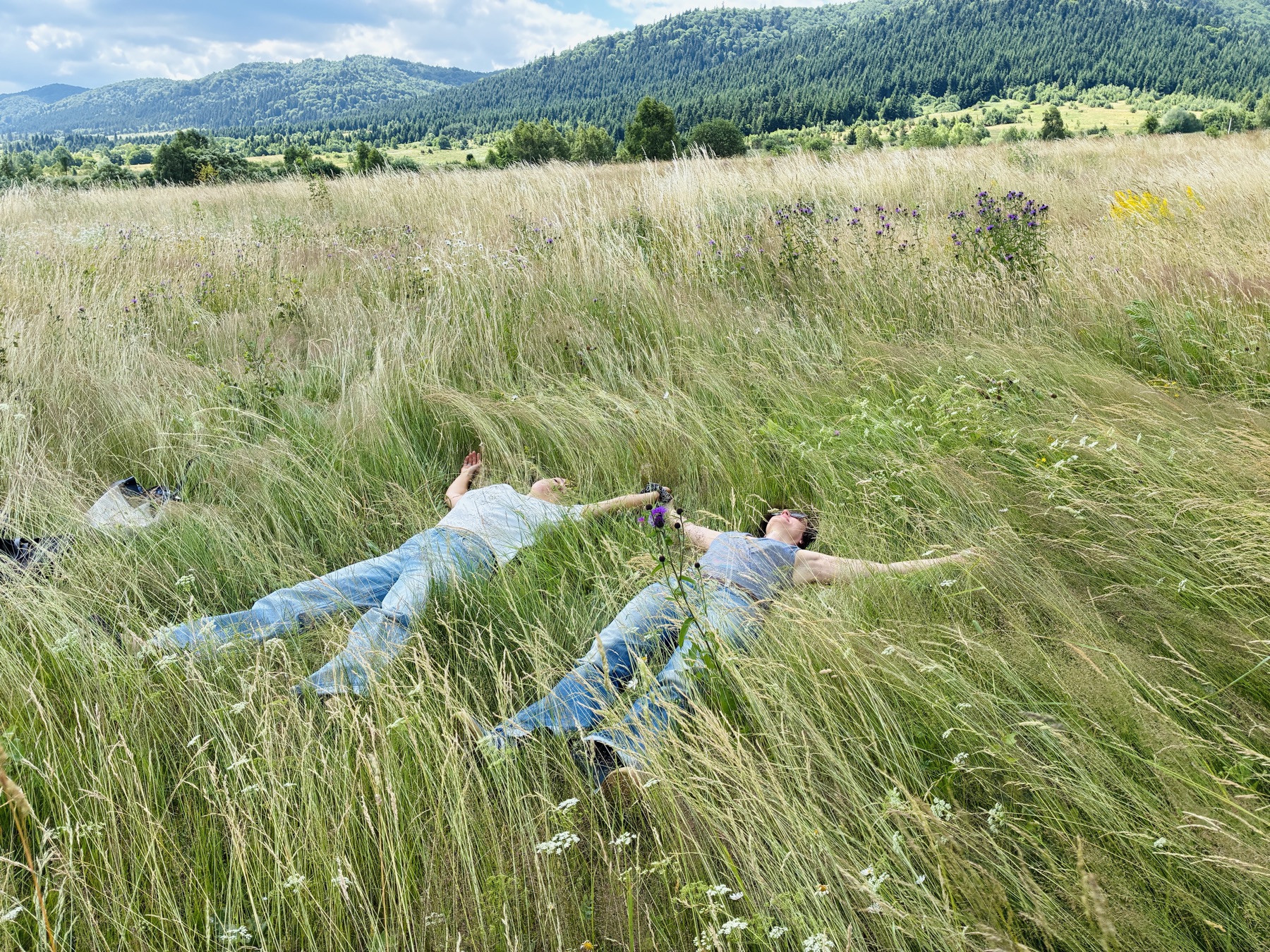 Zwei Frauen liegen entspannt in einer sommerlichen Bergwiese in den Karpaten